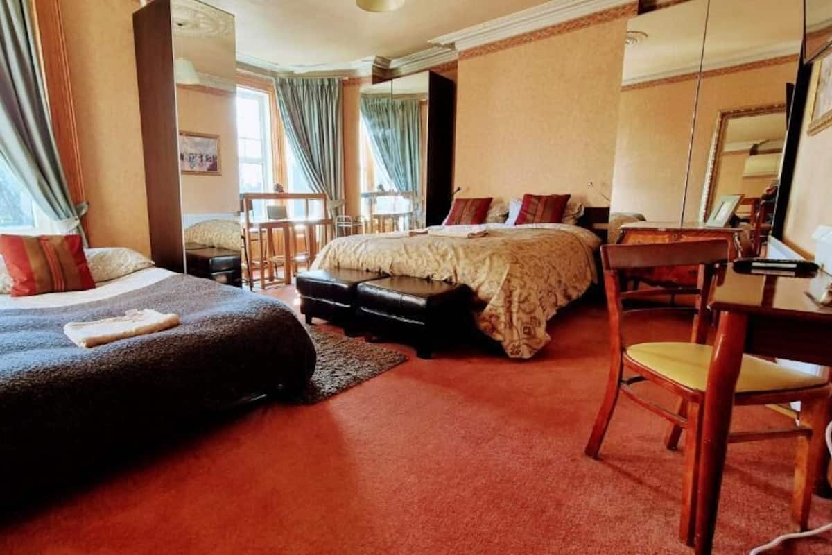 Habitación de hotel con dos camas, un escritorio, una silla y un ventanal grande.