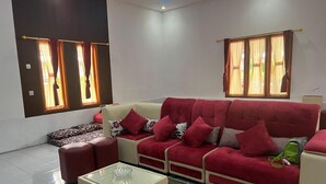 Una sala de estar con un sofá rojo, una mesa de centro de vidrio y una alfombra estampada.