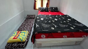 Un dormitorio pequeño y ordenado con una cama individual, un banco y una ventana con cortinas.