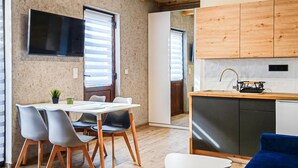A modern kitchen with wooden cabinets, a built-in stove, and a dining area with a table and chairs. - 2 bedroom beautiful home in Mrzezyno (Mrzezyno)