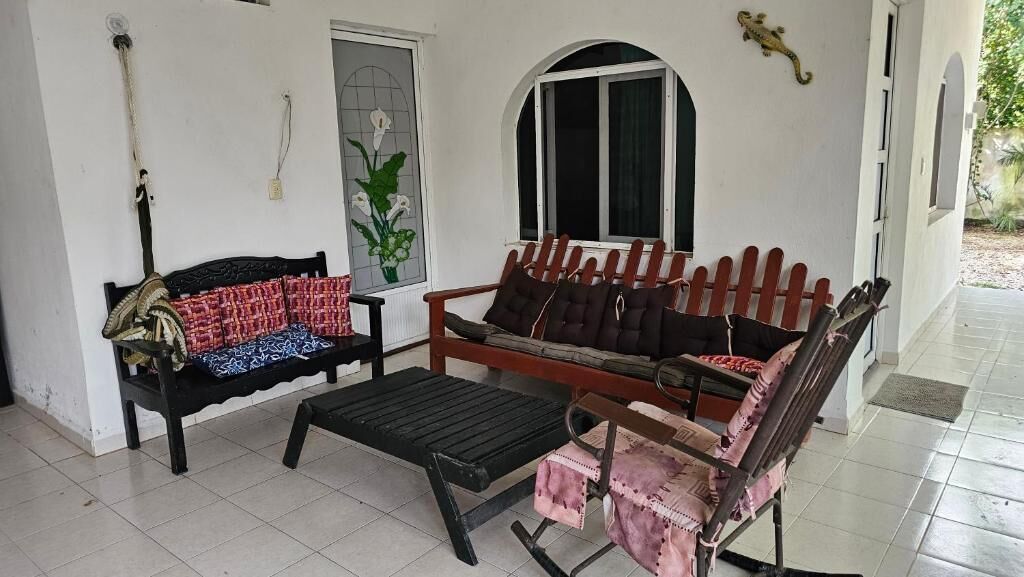 A room with a wooden bench, a small table, and a rocking chair.