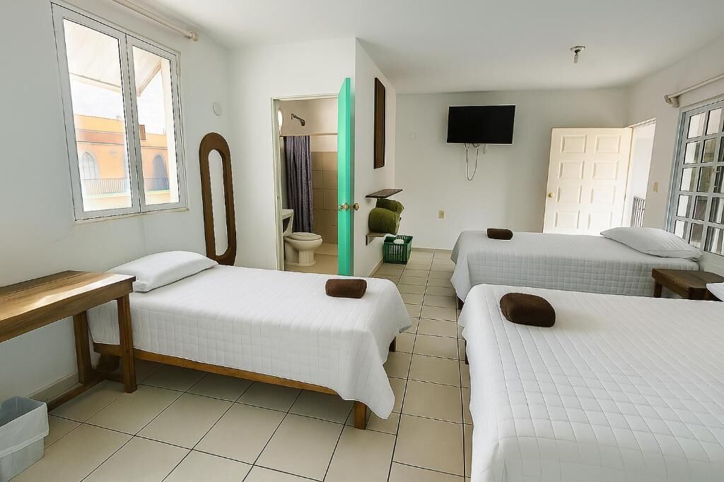 Habitación de hotel con dos camas, televisión, baño y ventana.