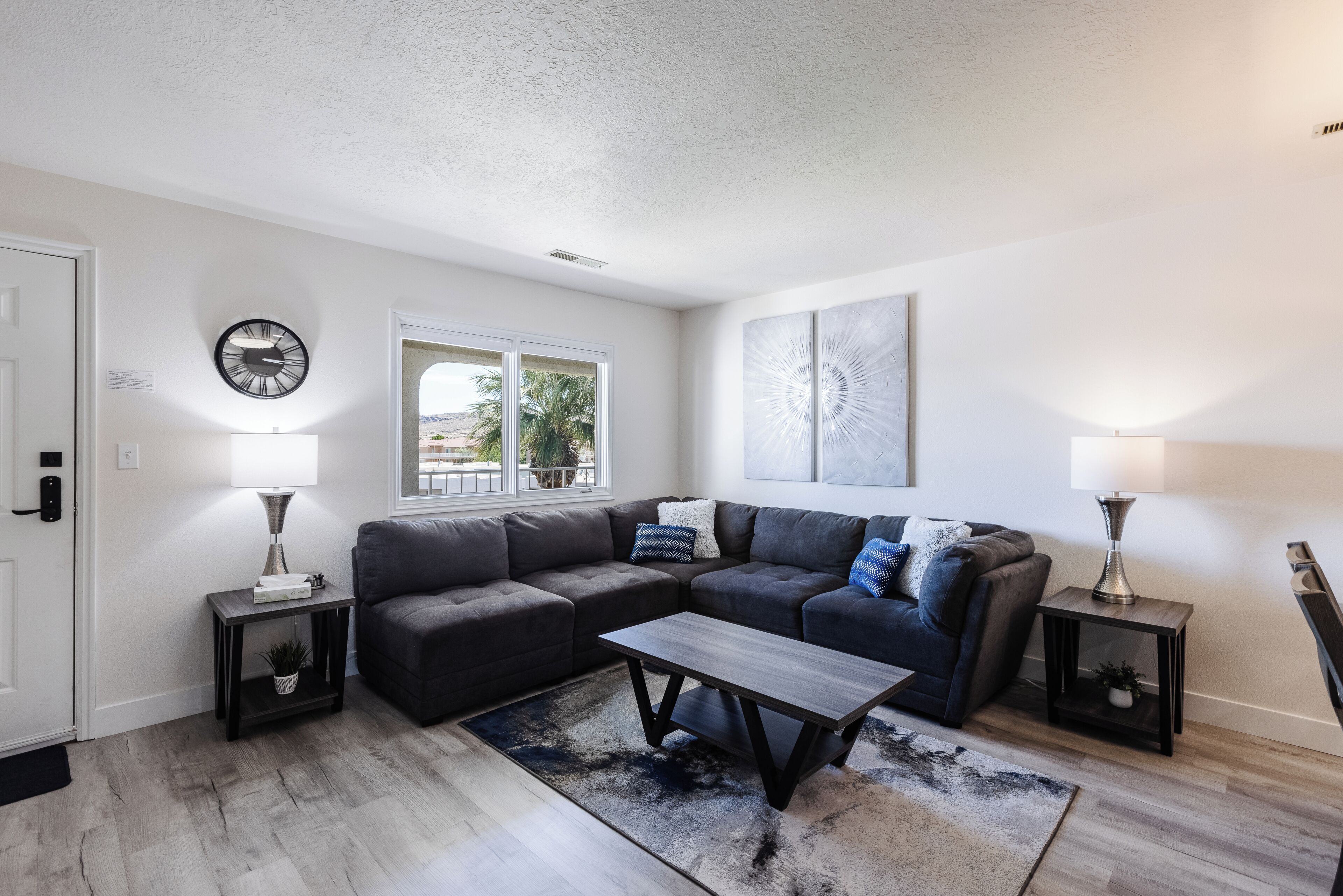 A modern living room with a sectional sofa, a coffee table, and two side tables with lamps.