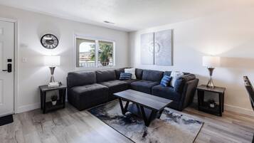 A modern living room with a sectional sofa, a coffee table, and two side tables with lamps.