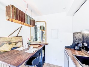 A modern kitchen with a wooden countertop, a hanging light fixture, and a large mirror. - La rivière St Goustan by Interhome (Auray)