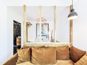 A room with a sofa, a hanging light fixture, and a mirror with a decorative frame. - La rivière St Goustan by Interhome (Auray)