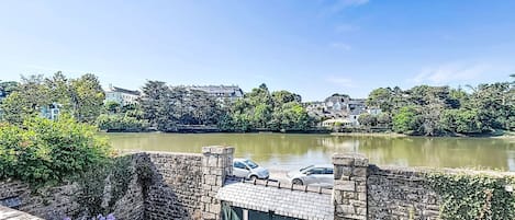 Uma ponte de pedra com um portão, um rio e edifícios ao fundo.