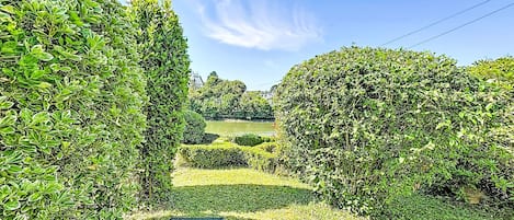 Un jardin avec des haies soigneusement taillées et une vue dégagée sur un lac.