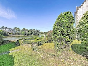 A riverside garden with a stone wall, a hedge, and a view of a river and buildings in the distance. - La rivière St Goustan by Interhome (Auray)