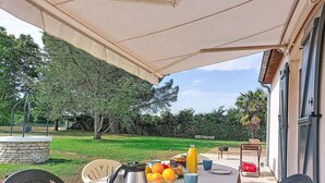 Un área de comedor al aire libre con una mesa dispuesta para el desayuno, una estructura de piedra y vistas a un jardín.