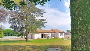 Una casa con techo de tejas, césped y un árbol.