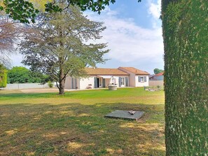 Ein Haus mit Ziegeldach, Rasen und Baum.