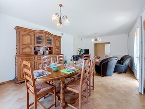 Un coin repas avec des chaises en bois, une table à manger en bois, un buffet aux portes vitrées et un lustre.