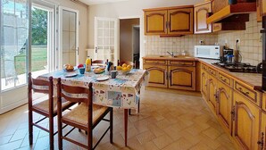 Una cocina con armarios de madera, una mesa de comedor con sillas, una ventana y un microondas.