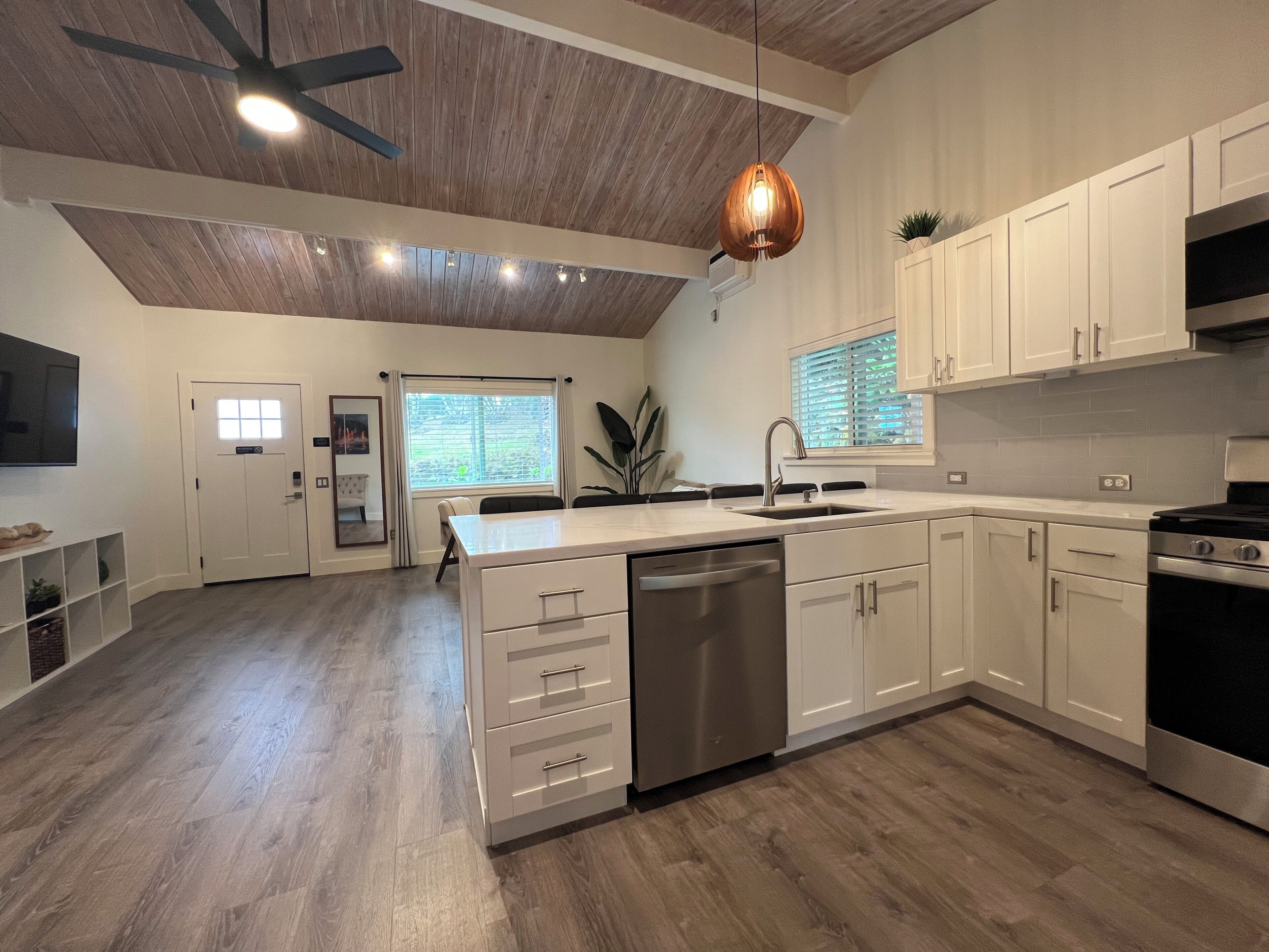 A modern kitchen with white cabinetry, a built-in dishwasher, and a stainless steel stove.