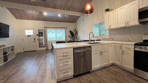 A modern kitchen with white cabinetry, a built-in dishwasher, and a stainless steel stove.
