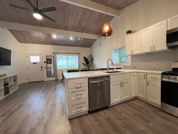 A modern kitchen with white cabinetry, a built-in dishwasher, and a stainless steel stove.