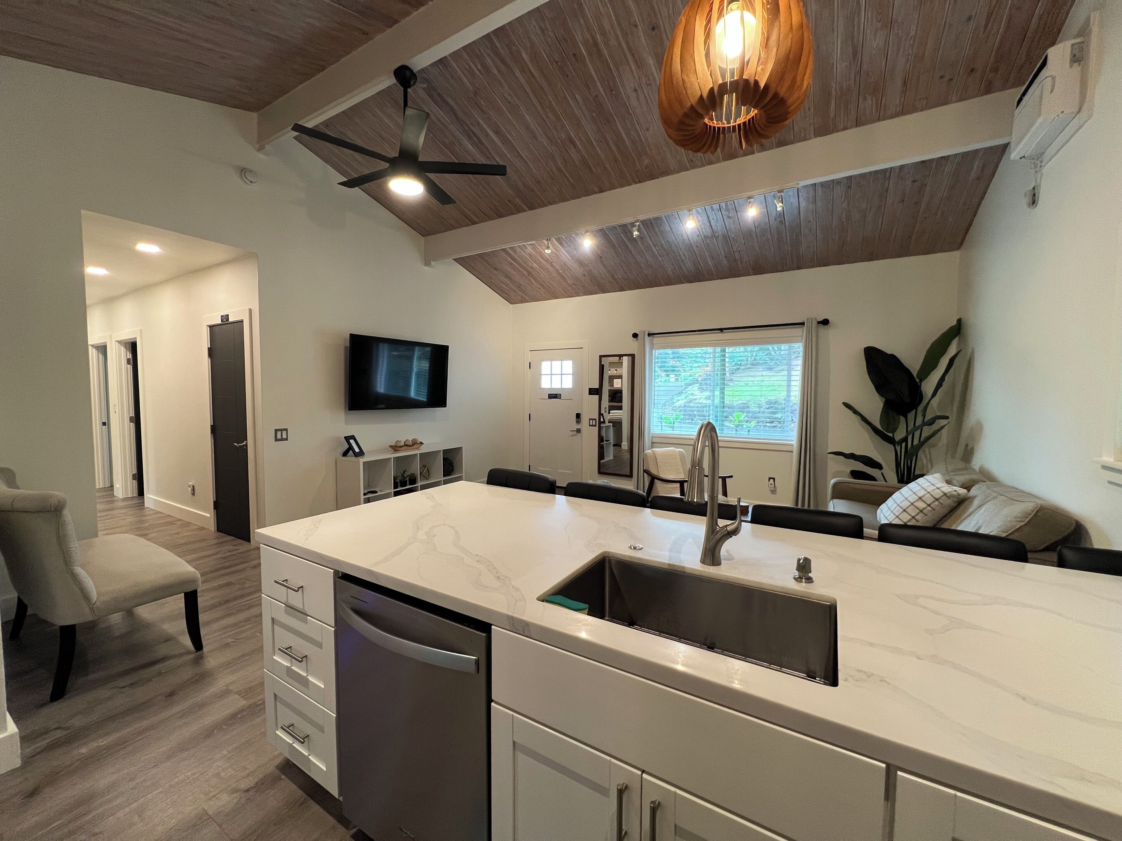 A modern kitchen with a marble countertop, built-in dishwasher, and a ceiling fan.