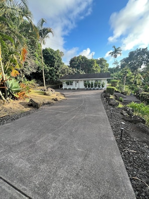 A paved pathway leading to a building with potted plants and a clear sky.