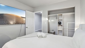 A modern hotel room with a large bed, a walk-in closet, and a view of a desert landscape.