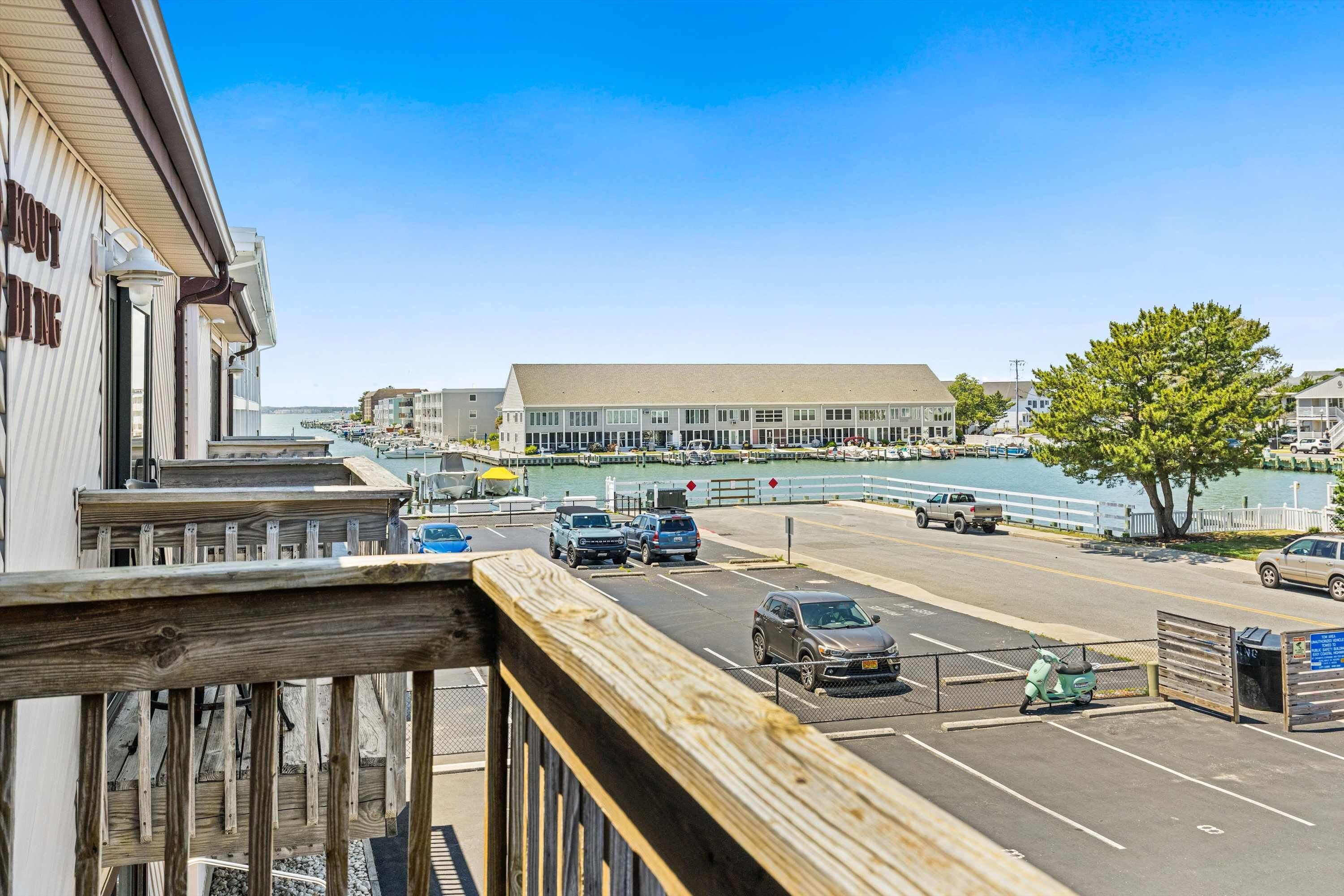 A waterfront view with a building, a dock, and parked vehicles.