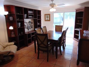 A dining area with a table and chairs, surrounded by wooden shelves with various items.