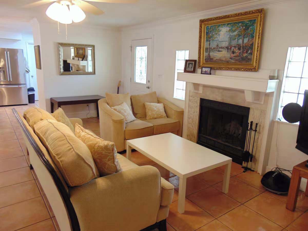 A living room with a sofa, a coffee table, a fireplace, and a painting on the wall.