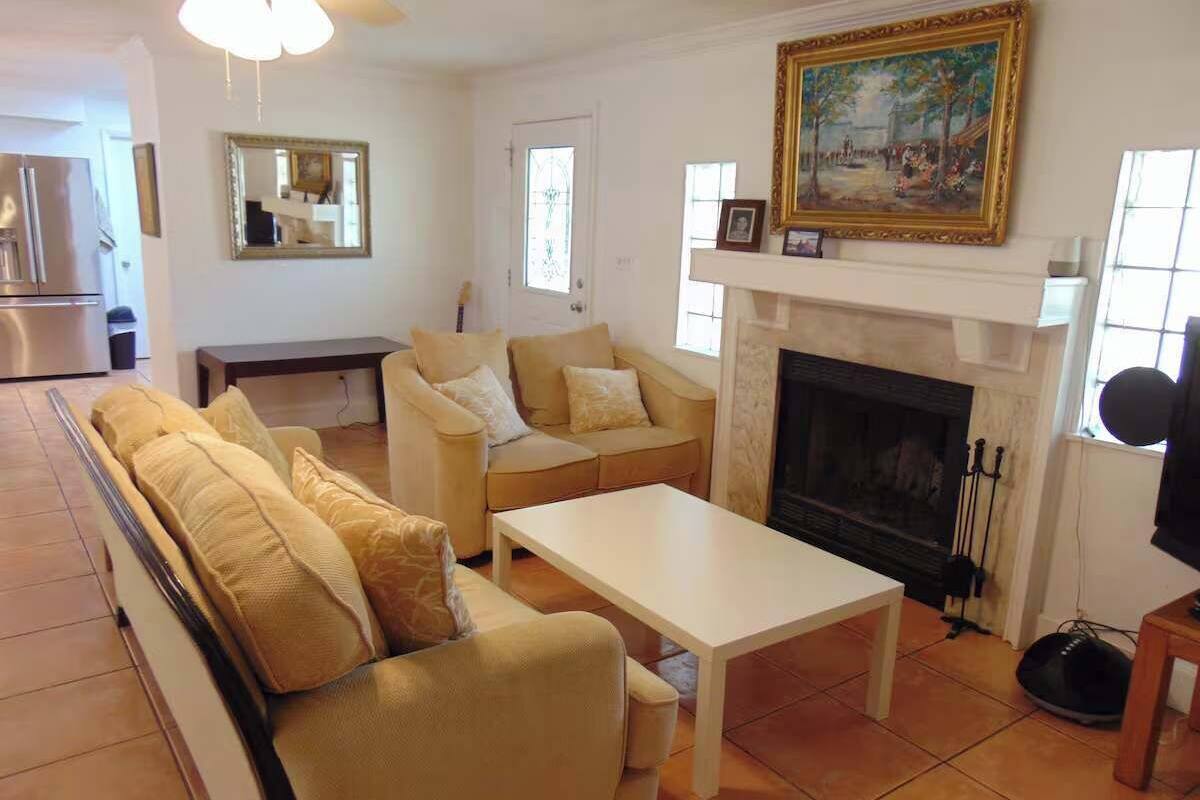 A living room with a sofa, a coffee table, a fireplace, and a painting on the wall.