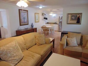 A living room with a sofa, a coffee table, and a dining area with chairs and a table.