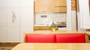Uma cozinha moderna com armários brancos, bancada de madeira e um banco vermelho.