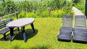 Um pátio com mesa e cadeiras, com vista para um lago e colinas arborizadas.