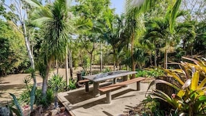 Un jardín con una mesa de picnic rodeada de diversas plantas y árboles.