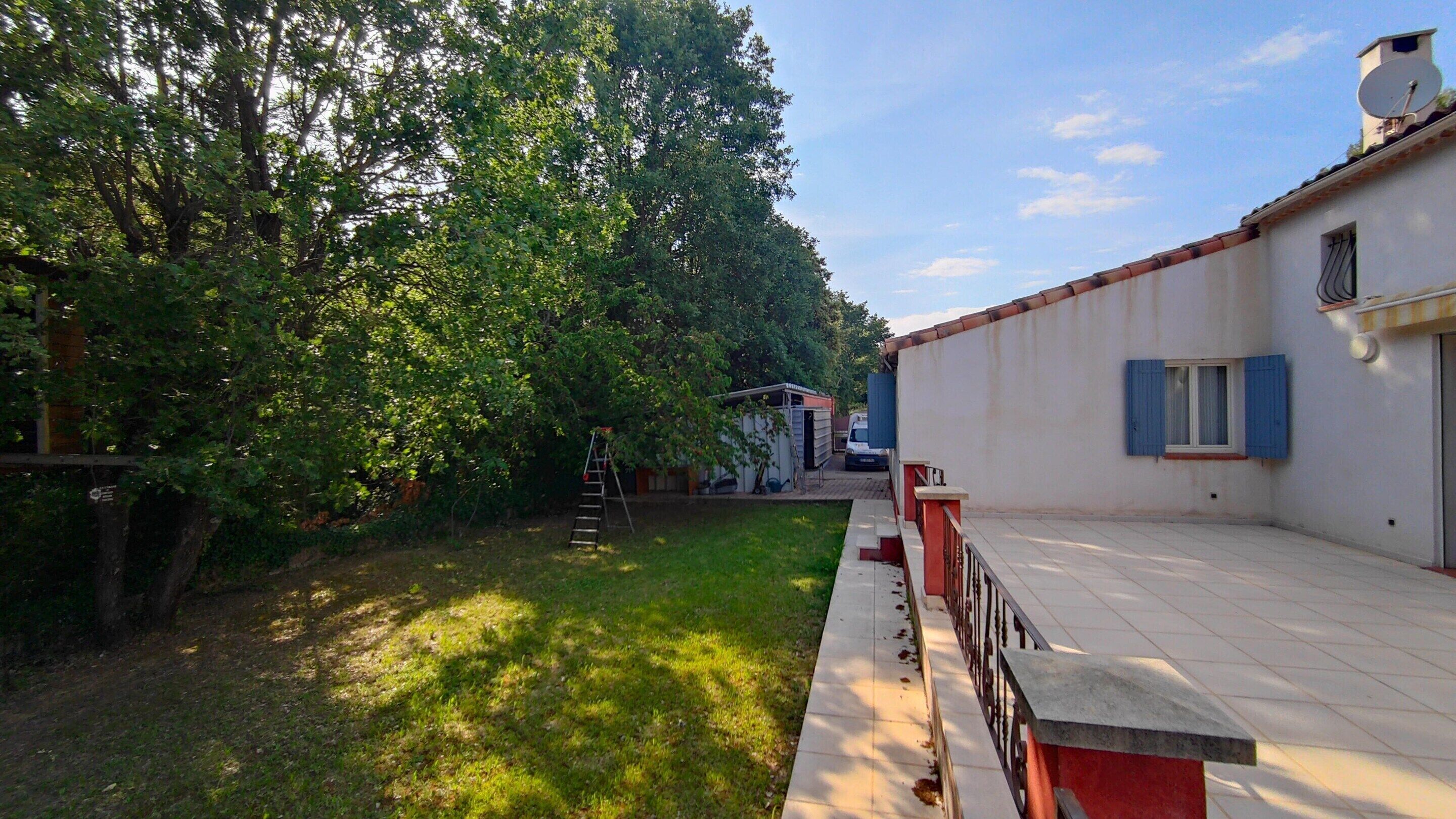 A courtyard with a lawn, a small shed, and a building with a satellite dish.