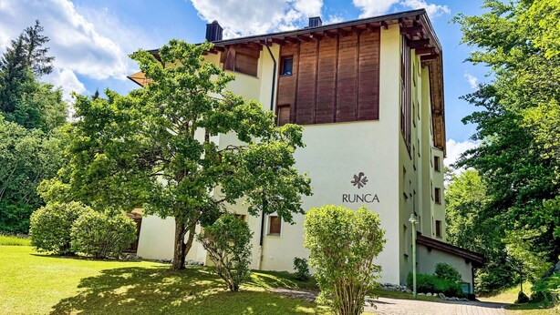 A building with the name 'RUNCA' on its facade, surrounded by trees and a paved driveway. - Runca 752 by Interhome (Flims)