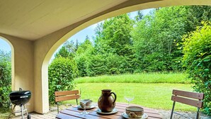 An outdoor patio with a round table, two wooden benches, a grill, and a pitcher. - Runca 752 by Interhome (Flims)