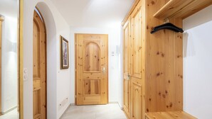 A hallway with wooden doors, a bench, and a coat rack. - Runca 752 by Interhome (Flims)