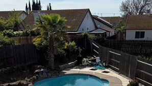 Un jardin avec une piscine, une clôture en bois et une maison en arrière-plan.