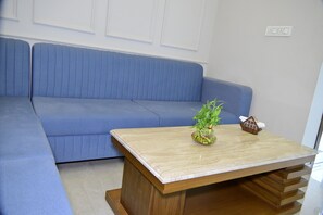 Um sofá azul com uma mesa de centro de madeira na frente.