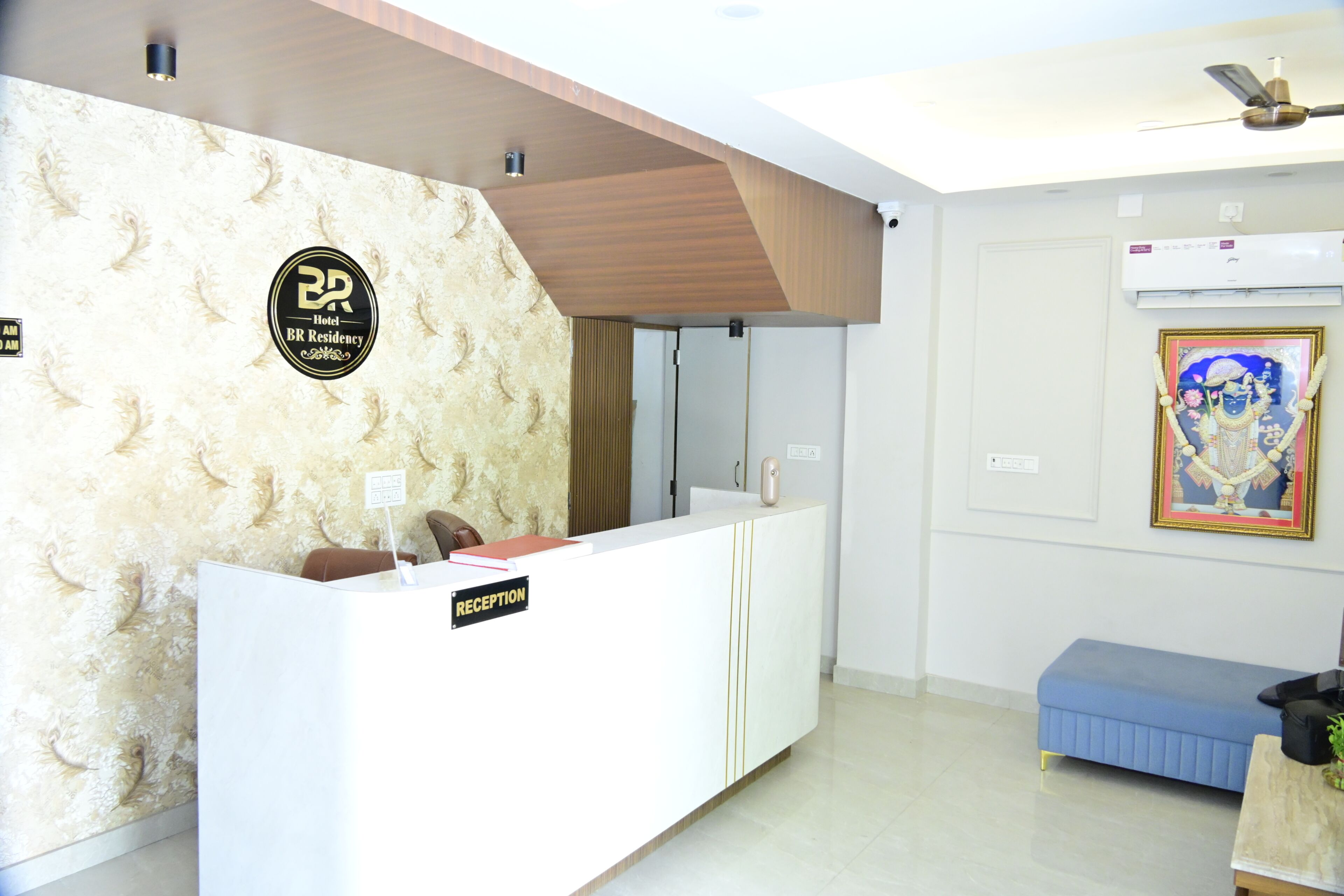 Zona de recepción de un hotel con diseño moderno, una mesa de recepción, un área de descanso y un equipo de aire acondicionado instalado en la pared.