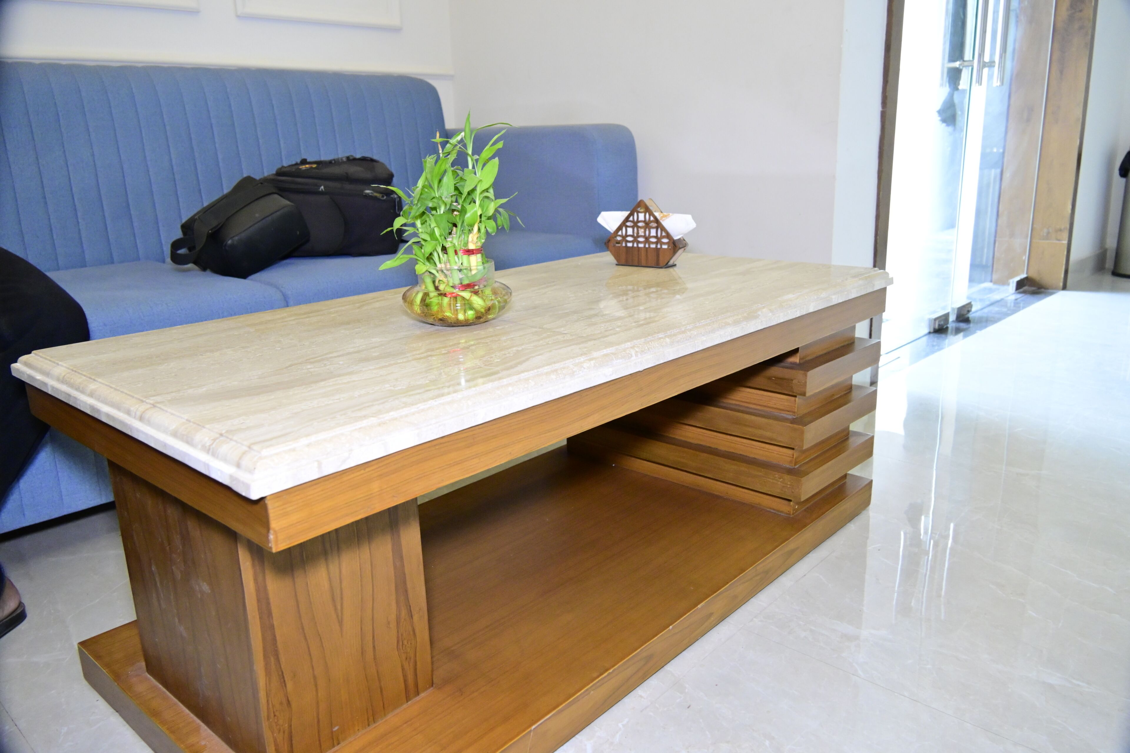 Una habitación con una mesa de madera, un sofá azul y una planta.