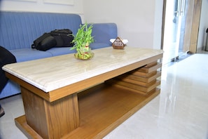 Ein Zimmer mit einem Holztisch, einem blauen Sofa und einer Pflanze.