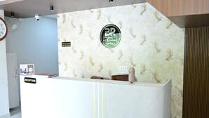 En hotellreception med en skylt för in- och utcheckning, en klocka och en logotyp på väggen.