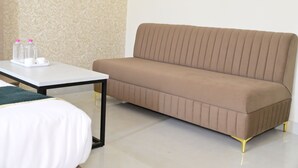 A modern hotel room with a beige sofa, a white table with water bottles, and a patterned wall. - Hotel BR Residency (Bikaner)