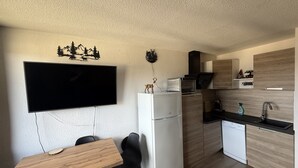 Kompakti keittiö, jossa on taulutelevisio, jääkaappi, mikroaaltouuni ja astianpesukone.