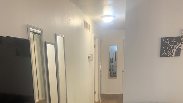 Un couloir avec un téléviseur à écran plat, trois miroirs, un canapé et un tableau accroché au mur.