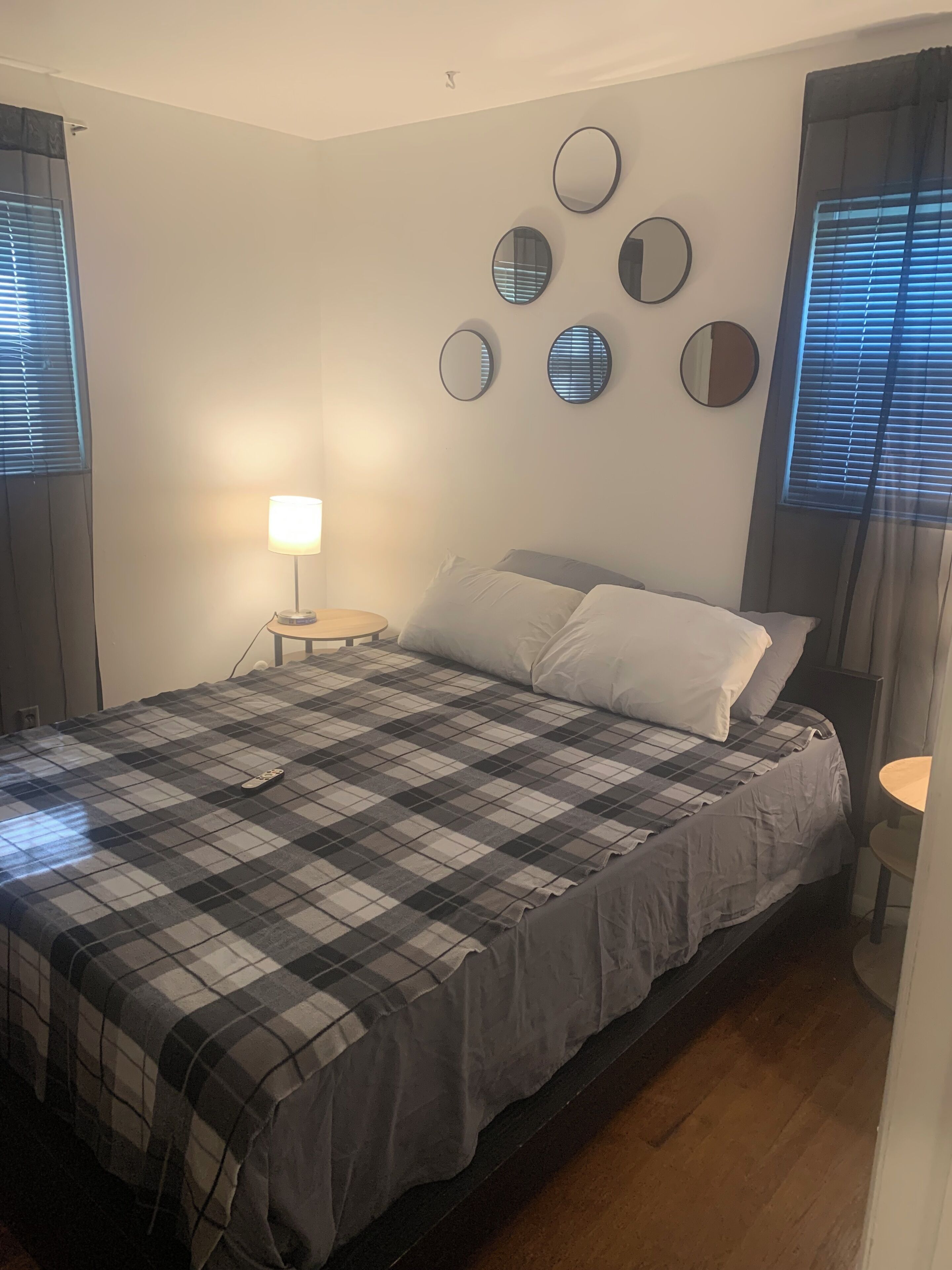 A bedroom with a bed, a bedside lamp, and a wall-mounted mirror.