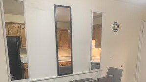 Un espace repas comprenant une table, des chaises et une cuisine visible à travers une fenêtre.