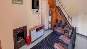 Ein Wohnzimmer mit Kamin, einer Sofagarnitur, einem Fernseher und einer Treppe.
