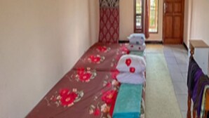 Ein Zimmer mit einem Bett, einem kleinen Tisch und einem Fenster mit Vorhängen.