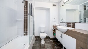Ein modernes Badezimmer mit Dusche, Toilette und Waschbecken, mit weißen und braunen Fliesen.